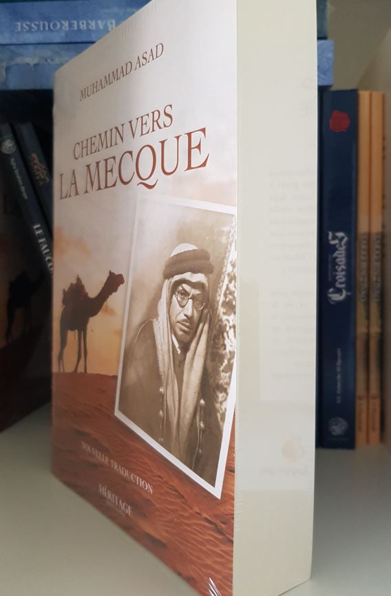 Couverture du livre Chemin vers La Mecque de Muhammad Asad, édition française chez Héritage Éditions. Une scène chaleureuse du désert au coucher du soleil, avec un chameau chargé avançant sur les dunes, symbolise le voyage spirituel. En bas à droite, une photo sépia de l’auteur en tenue traditionnelle arabe souligne le caractère autobiographique de l’ouvrage.