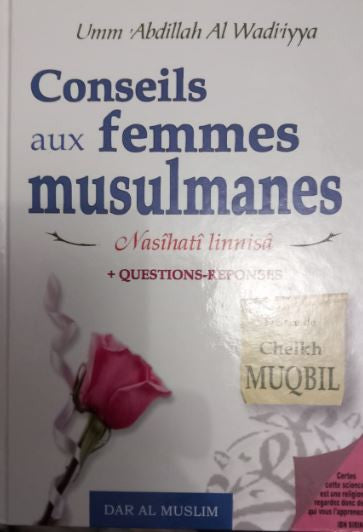 Photographie du livre Conseils aux femmes musulmanes de Umm ‘Abdillah Al-Wâdiriyya, posé debout sur une surface en bois clair, avec une couverture blanche décorée d’une rose rose et de calligraphies colorées en bleu et rouge. Le titre est accompagné d’un encart doré mentionnant Cheikh Muqbil, dans une ambiance douce et chaleureuse