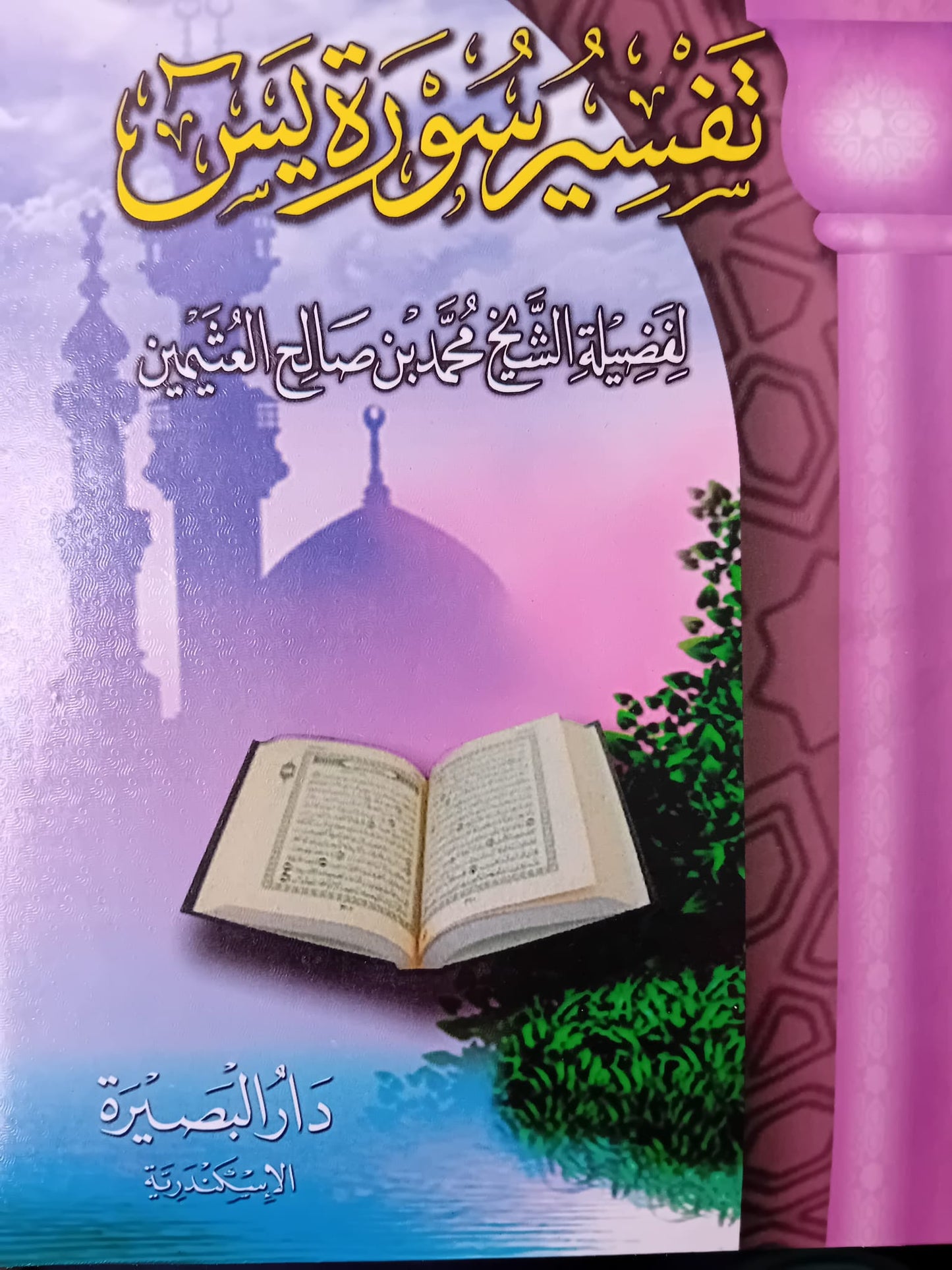 Photographie de la couverture du livre Tafsir Sourate Yâ-Sîn du cheikh Mohammed Ibn Sâlih Al-‘Uthaymîn, dans une édition colorée publiée par Dar Al-Bassira (Alexandrie). L’arrière-plan présente un ciel dégradé de rose et violet, des minarets en silhouette, une colonne mauve à motif géométrique et un Coran ouvert posé au-dessus d’un paysage d’eau et de verdure, dans une composition très vive et spirituelle