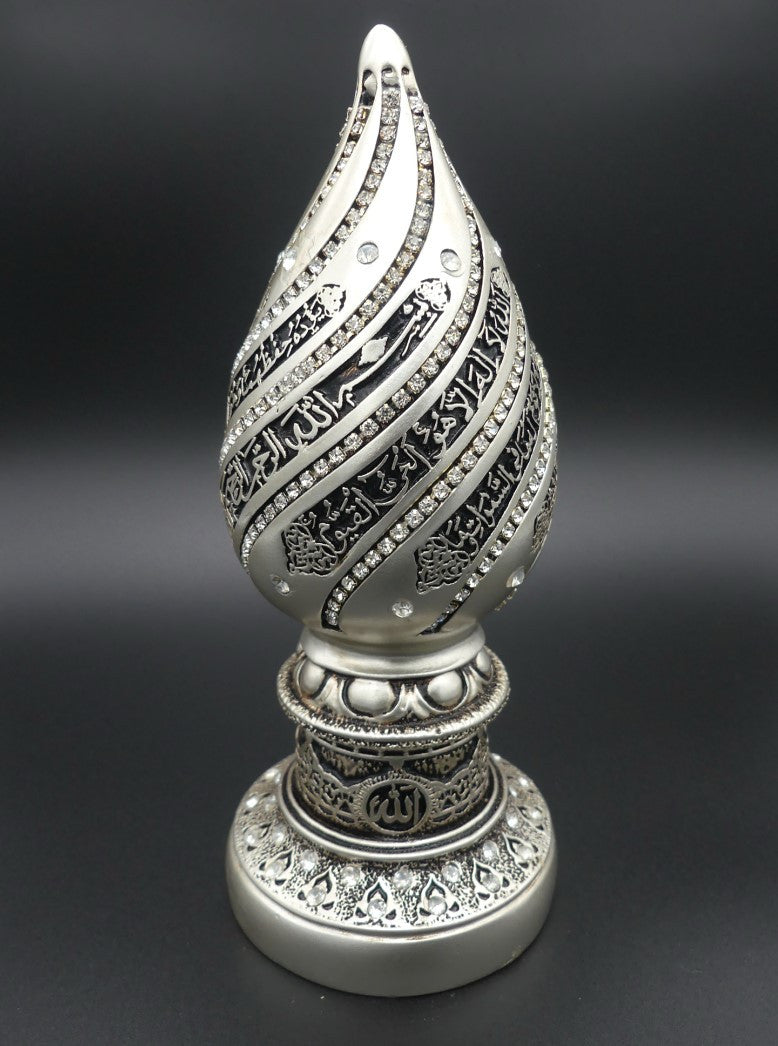 Élégant bibelot décoratif de couleur argentée, en forme de goutte élancée, orné de calligraphies arabes et de pierres scintillantes. Sa base finement ciselée arbore le nom d’Allah et des motifs géométriques inspirés de l’art islamique. Un objet raffiné, idéal pour sublimer une pièce avec spiritualité et distinction.