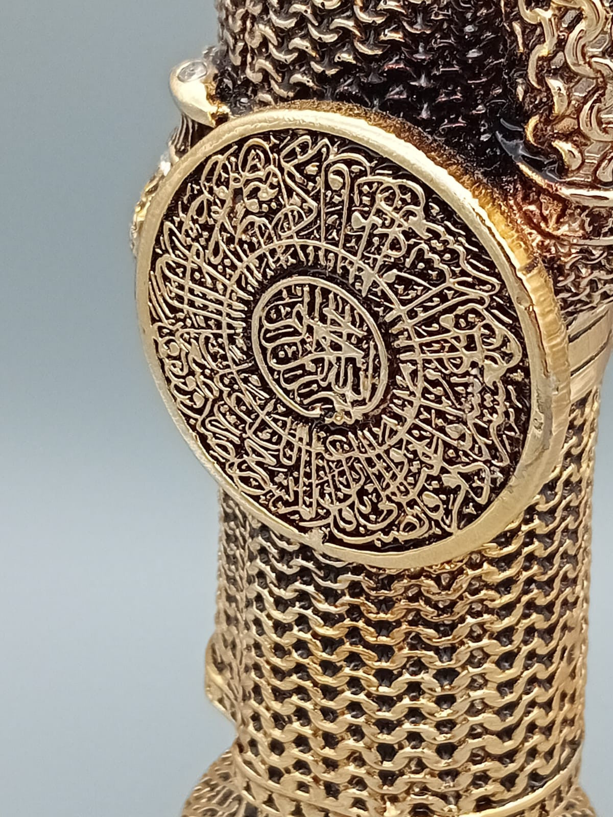 Statue décorative d’un soldat ottoman en armure, tenant un bouclier orné de calligraphies, exposée sur une étagère en bois aux côtés de livres anciens.