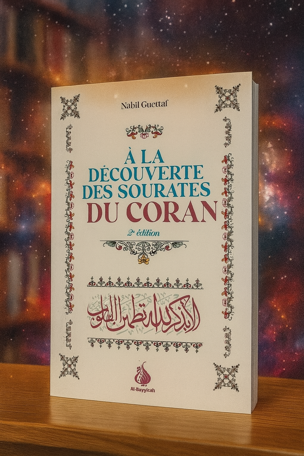 Couverture du livre "À la découverte des sourates du Coran" de Nabil Guettaf, 2ᵉ édition, décorée de motifs floraux et calligraphiques, posée sur une étagère avec un fond céleste et une ambiance chaleureuse.