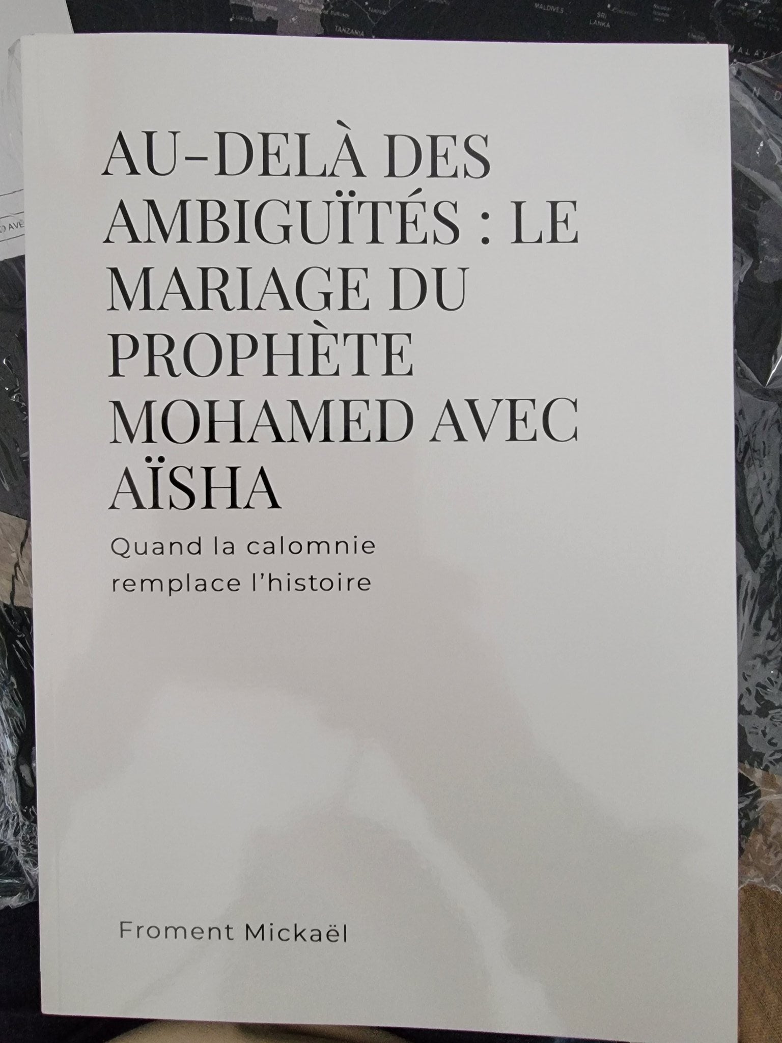 Livre “Au-delà des ambiguïtés : Le mariage du Prophète Mohamed avec Aïsha” de Froment Mickaël, édition brochée blanche en mise en scène 3D élégante avec décor oriental et ambiance chaleureuse.