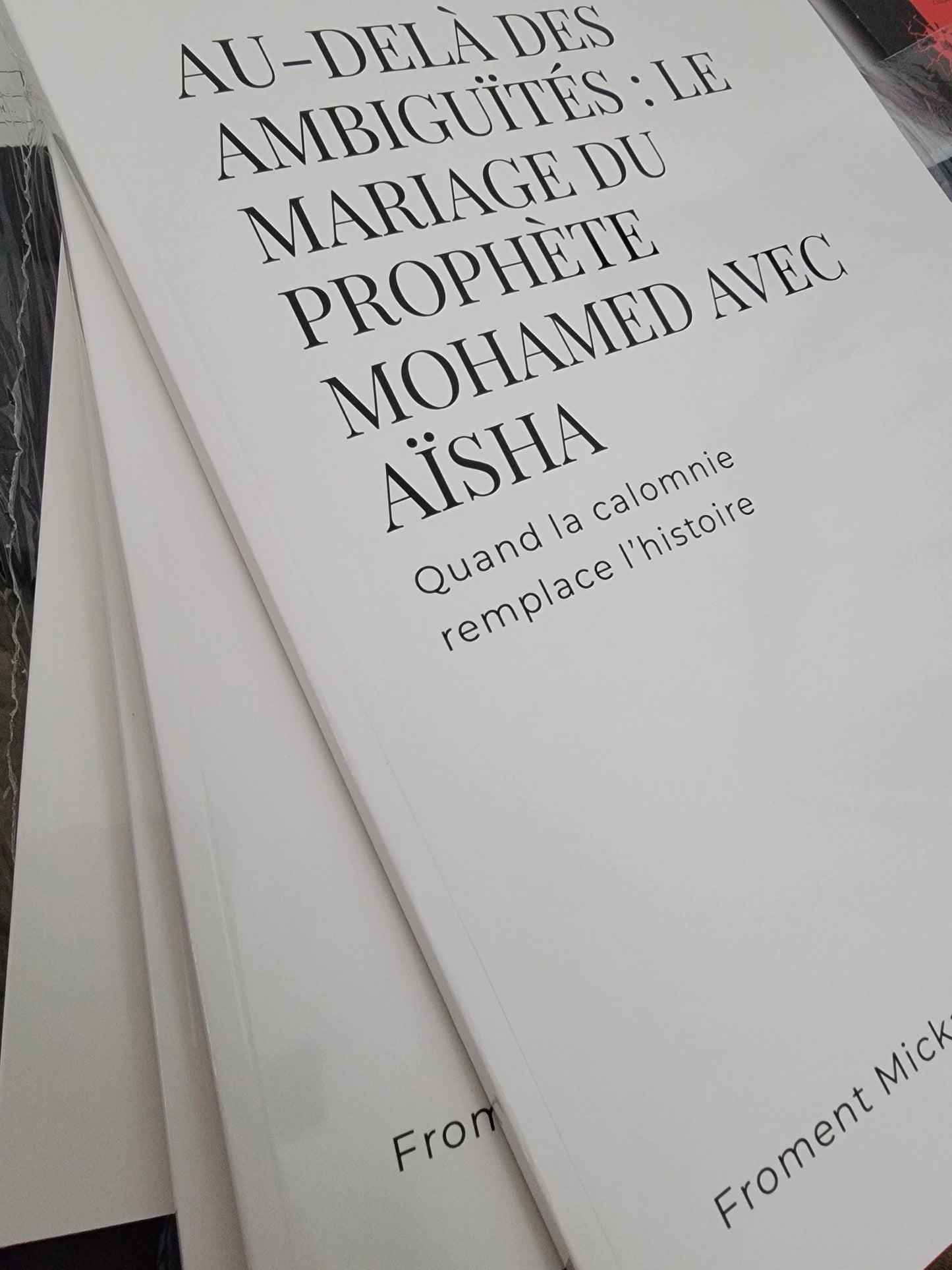 Livre “Au-delà des ambiguïtés : Le mariage du Prophète Mohamed avec Aïsha” de Froment Mickaël, édition brochée blanche en mise en scène 3D élégante avec décor oriental et ambiance chaleureuse.